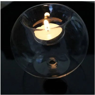 Handmade round hollow glass candle holder with openwork holes, shown on a table.