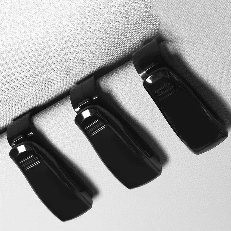 Black plastic car sunshade clip holding sunglasses and parking ticket