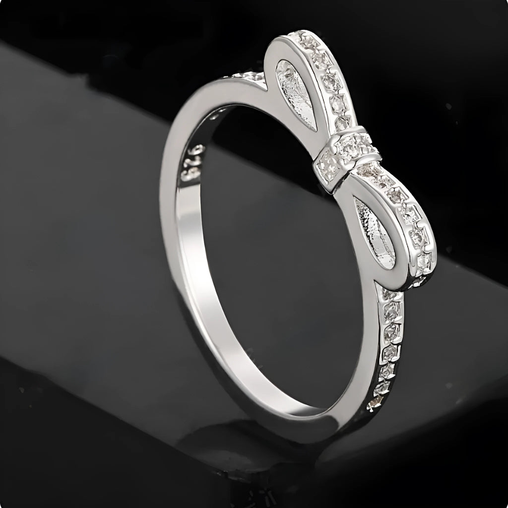 Silver bow-shaped ring with rhinestone and zircon crystal detailing on electroplated metal