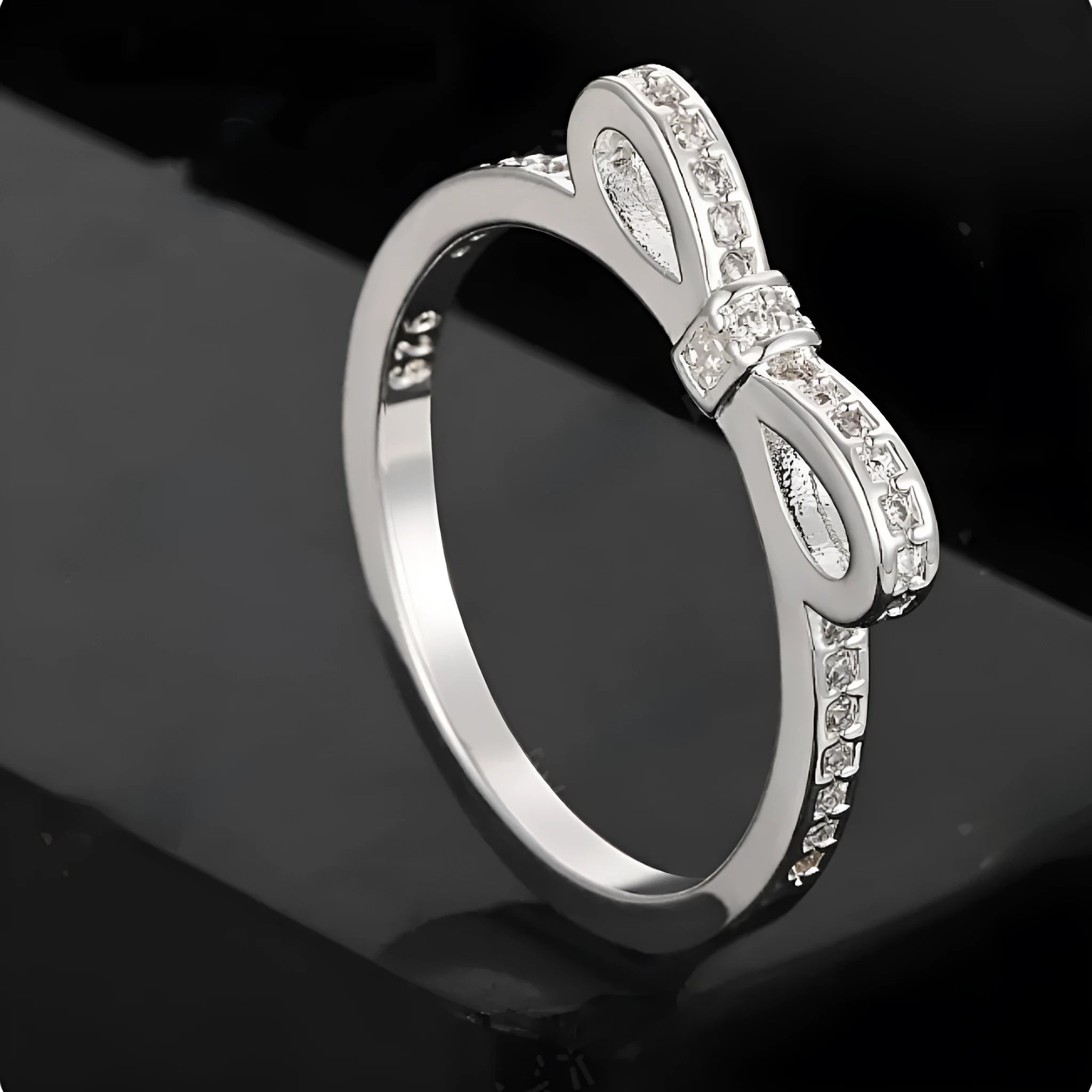 Silver bow-shaped ring with rhinestone and zircon crystal detailing on electroplated metal