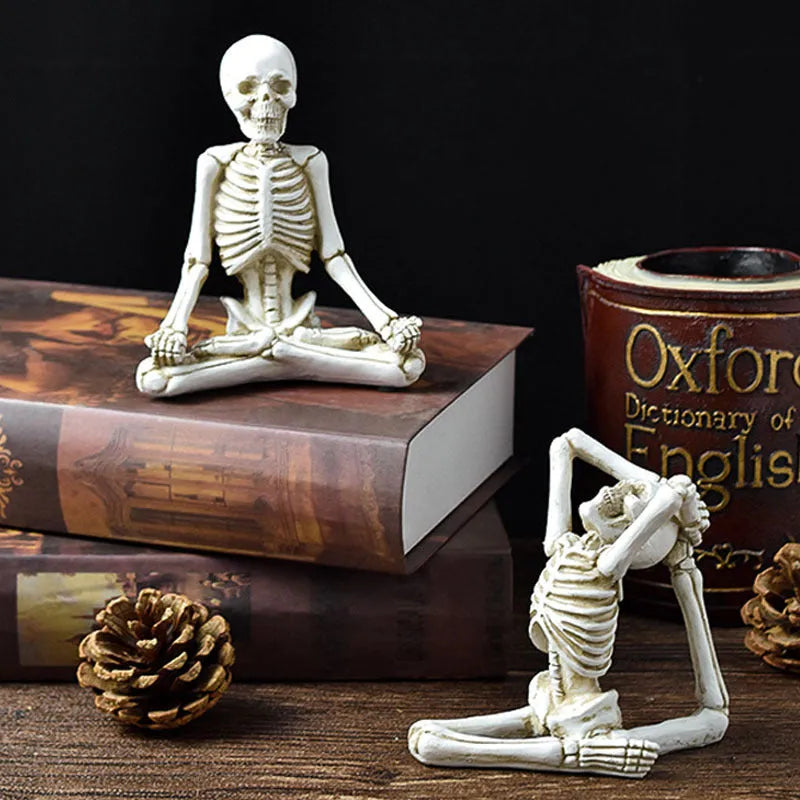Detailed resin ornament of a yoga pose skeleton skull on a desktop, shown in black and white colour options.
