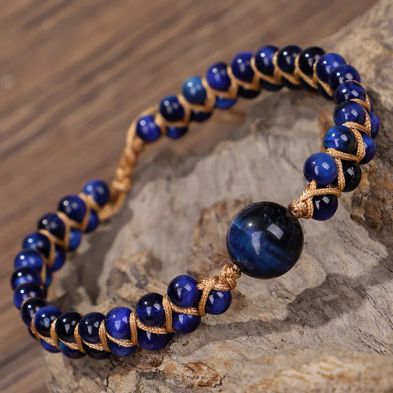 Handwoven geometric pull bracelet made from blue Tigereye stone on a wrist.