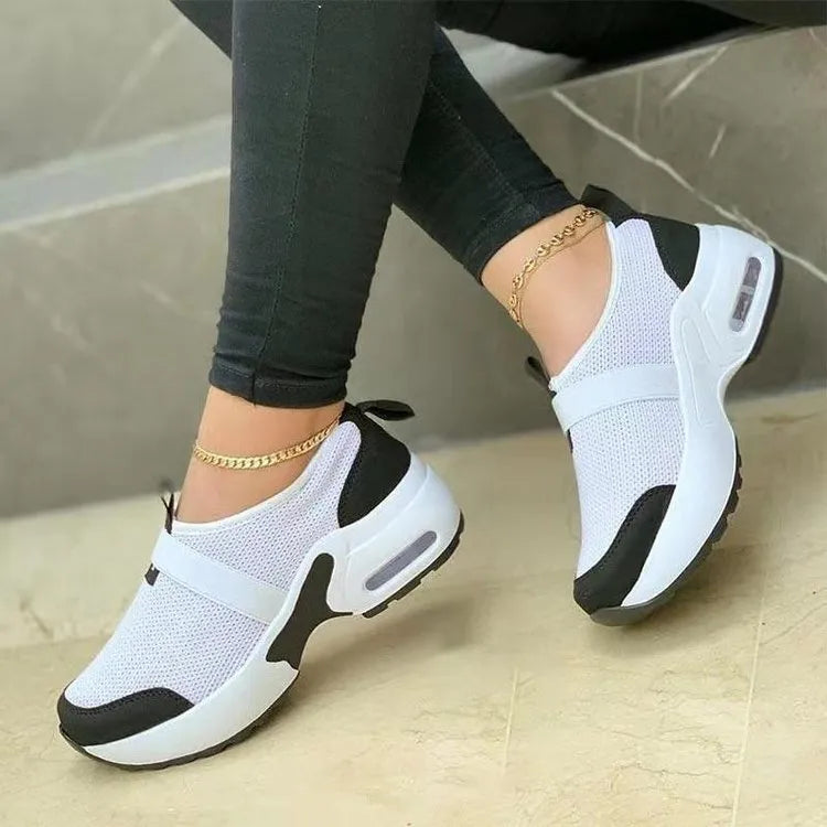 Women's white mesh flat sneakers with a rubber sole shown from the side.