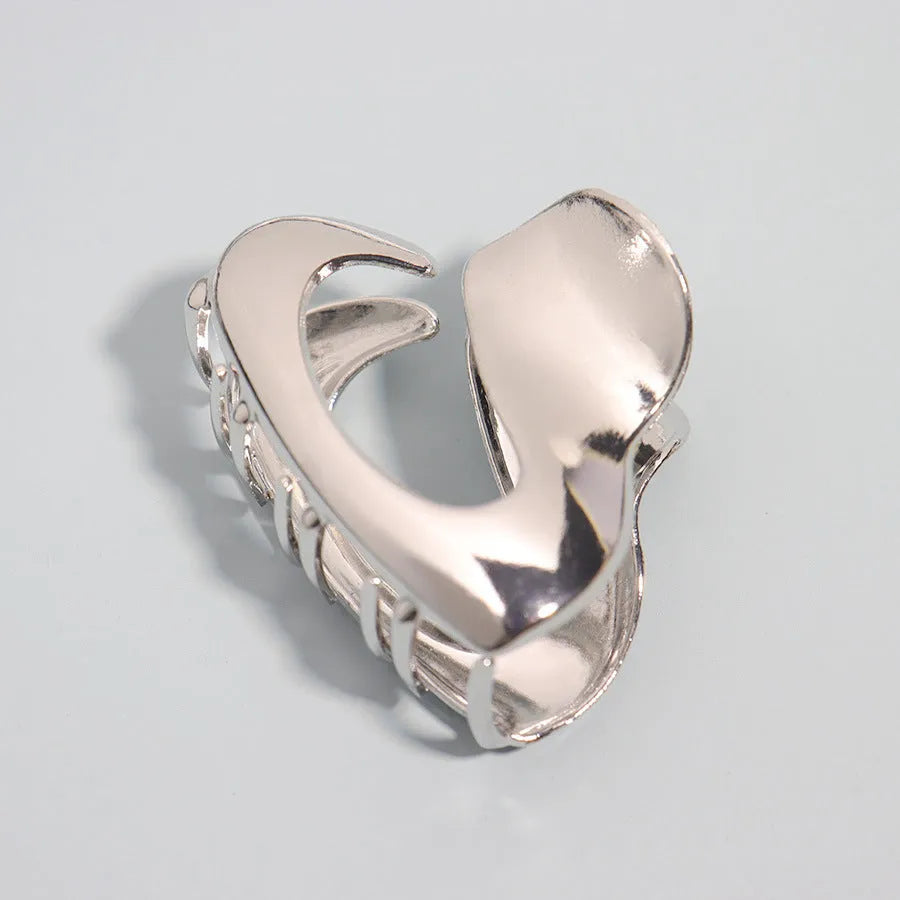 Silver metal hair claw clip assortment showing bows, waves, pearl designs, and geometric shapes from 4cm to 13.5cm