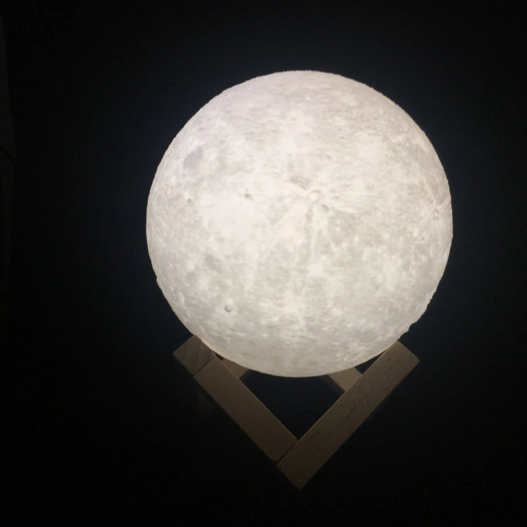 3D printed moon lamp showing detailed craters, on wooden stand with touch metal ring at base.