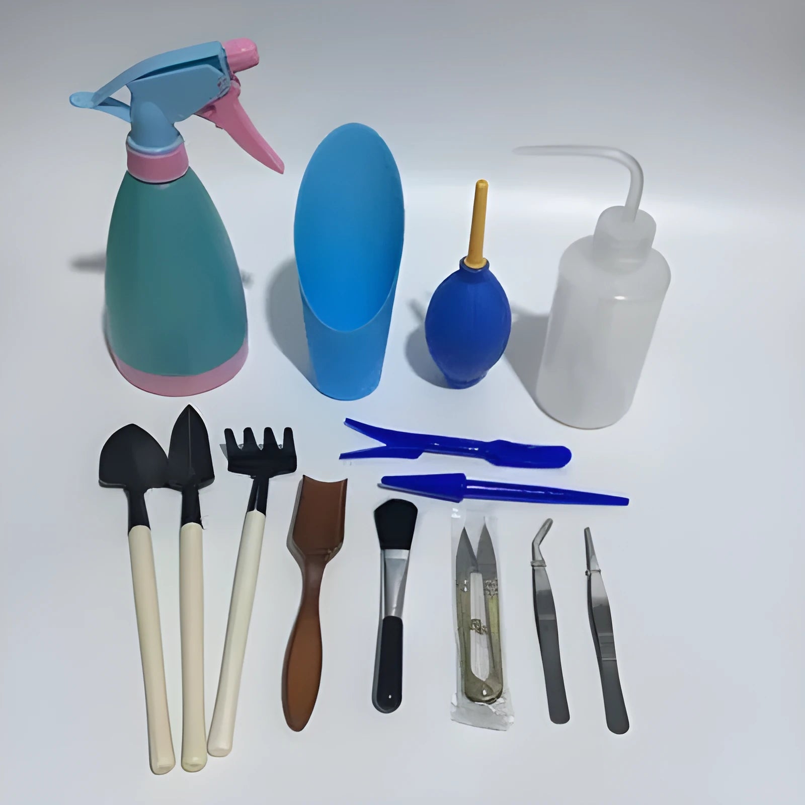 Succulent gardening tool set with plastic watering can, mini shovel, tweezers, and small brush arranged for indoor plant care