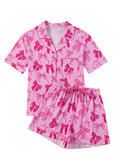 Pink women's pajama set with bow print, featuring a top and trousers made from lightweight polyester fabric.