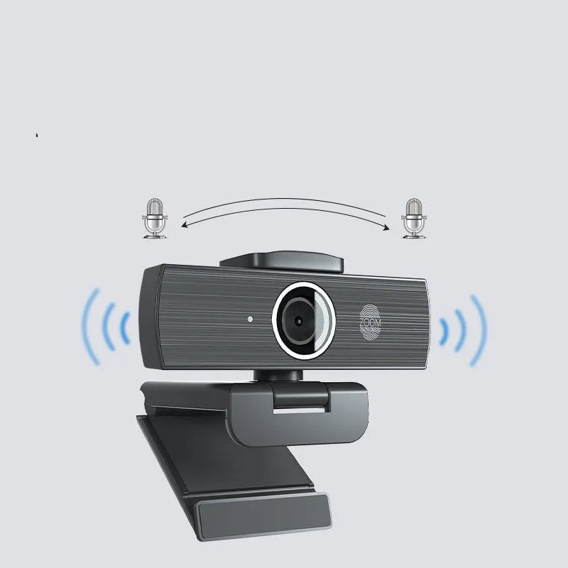Black USB webcam with magnetic privacy cover on desk next to computer monitor