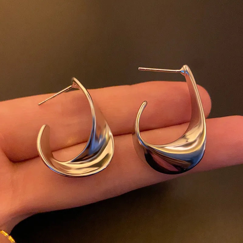 Gold and silver twisted geometric metal earrings with round shape and electroplated finish