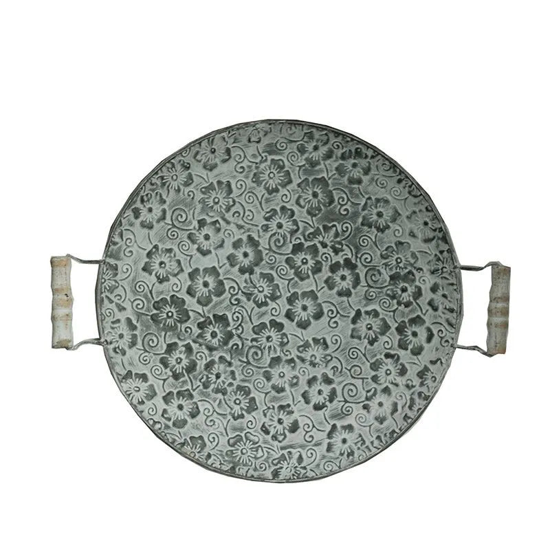 Round wrought iron storage tray in a classic metal colour on a wooden surface.