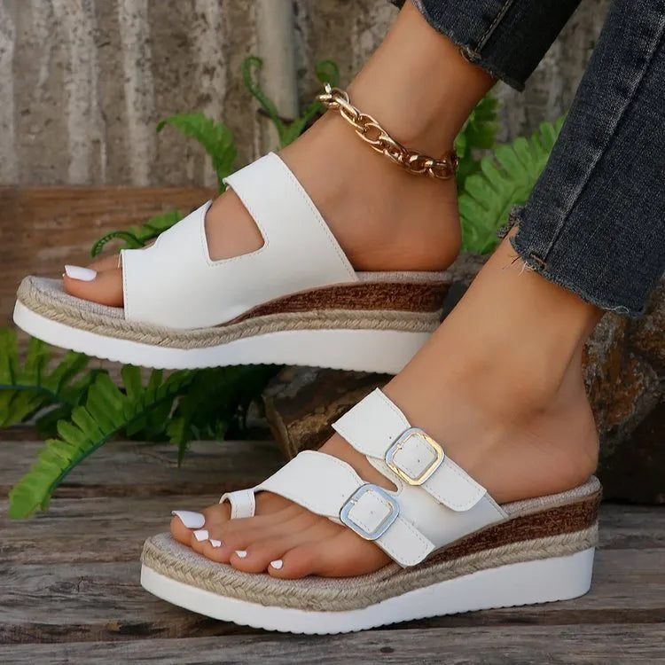 White wedge heel sandals with woven patent leather upper and peep toe design on neutral background