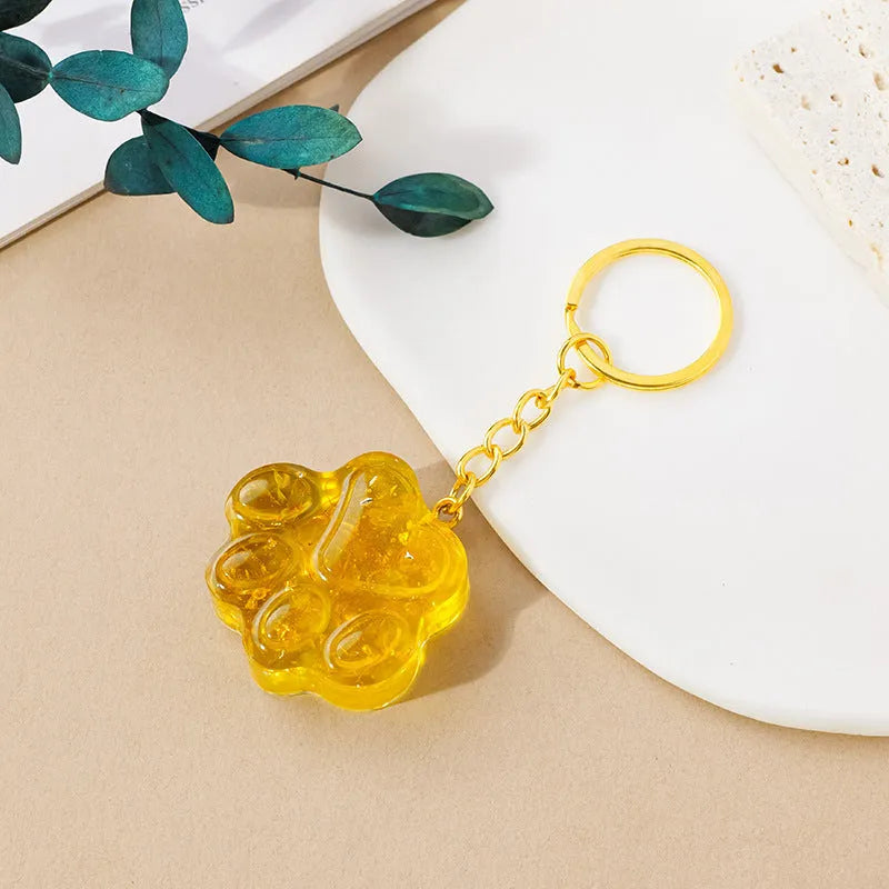 Natural crystal cat's paw shaped pendant on a silver keychain ring, shown in a random colour.