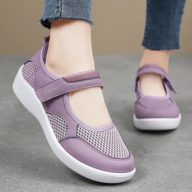 Women's grey mesh slip-on casual shoes with Velcro strap fastening on a flat sole.