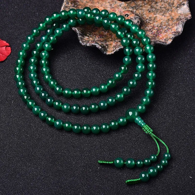 Natural green agate 108-bead bracelet with pendant in Thangka style on a wrist.
