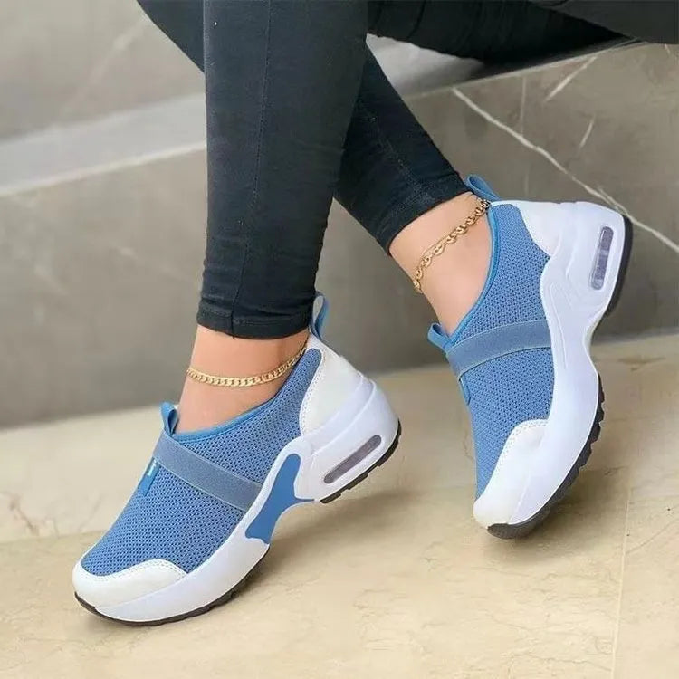 Women's white mesh flat sneakers with a rubber sole shown from the side.