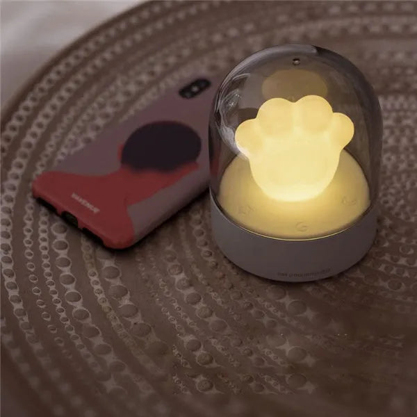 Grey cat paw shaped USB rechargeable night light and music box with soft glowing light.