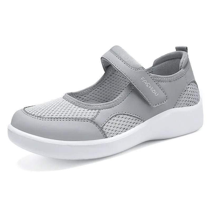 Women's grey mesh slip-on casual shoes with Velcro strap fastening on a flat sole.