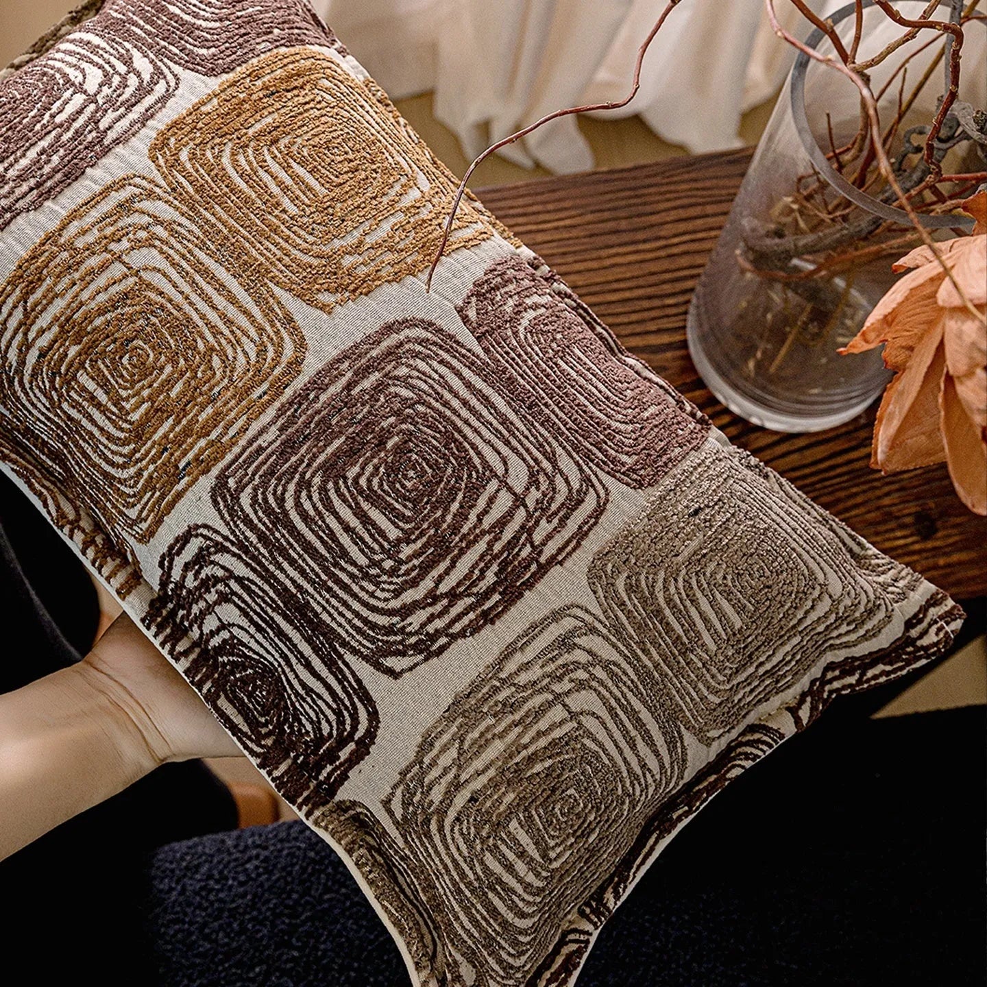 Cream and coffee-coloured abstract coil pattern on a square polyester pillow cover.