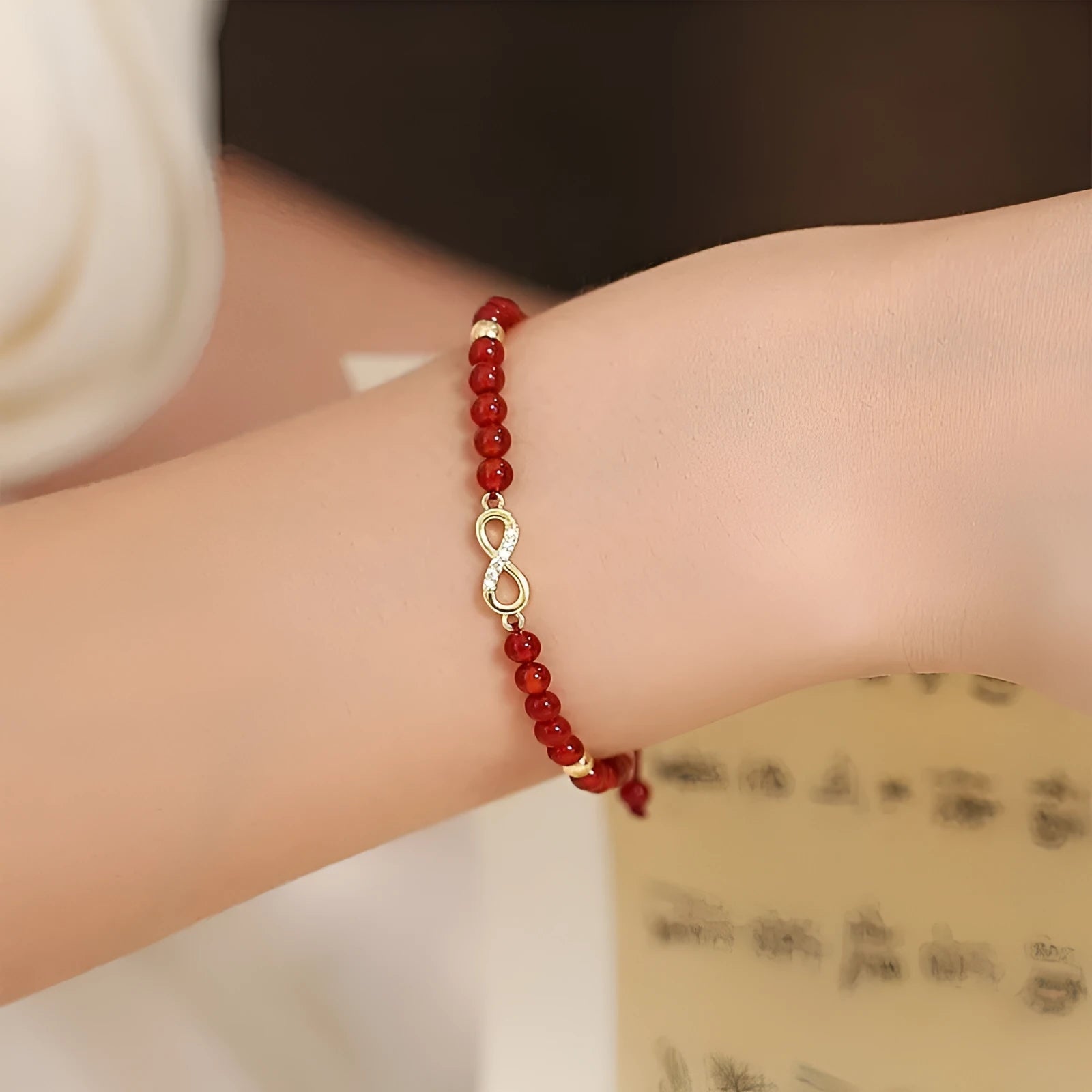 Hand-woven red agate bead bracelet with ethnic design on a wrist.