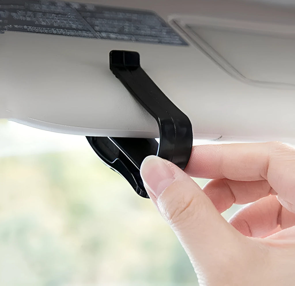 Black plastic car sunshade clip holding sunglasses and parking ticket