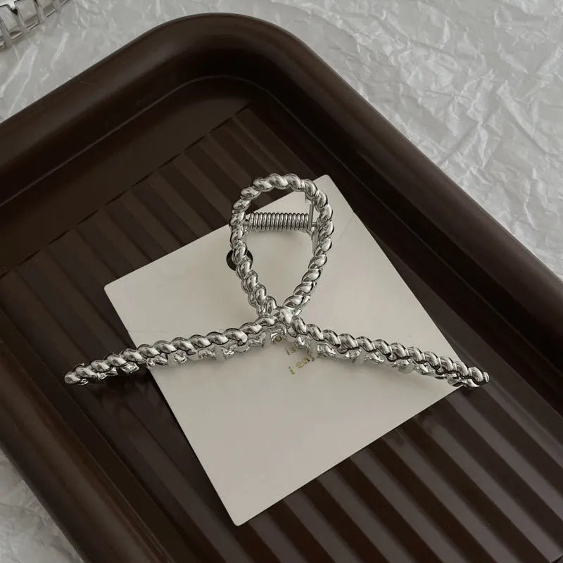 Silver metal hair claw clip assortment showing bows, waves, pearl designs, and geometric shapes from 4cm to 13.5cm
