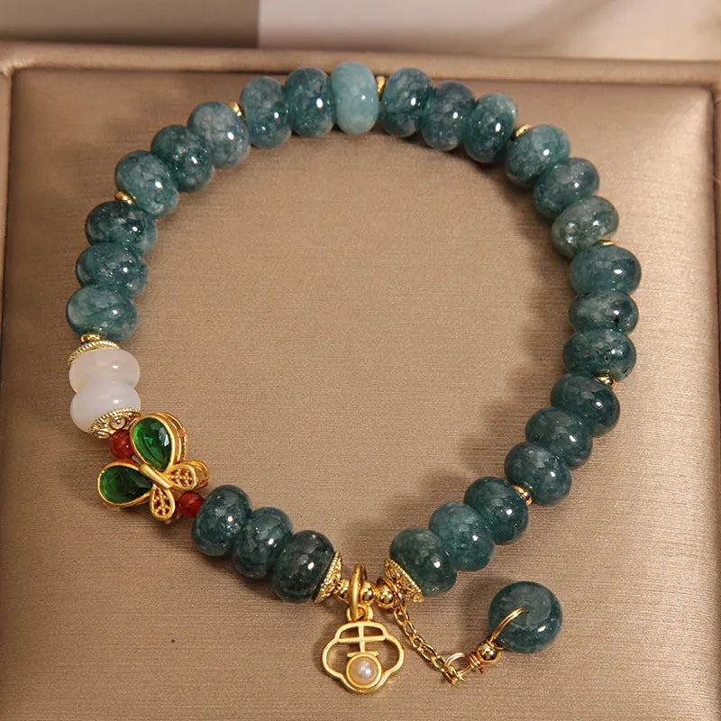 Blue water jade abacus bead bracelet with butterfly charm and white agate on an alloy band.