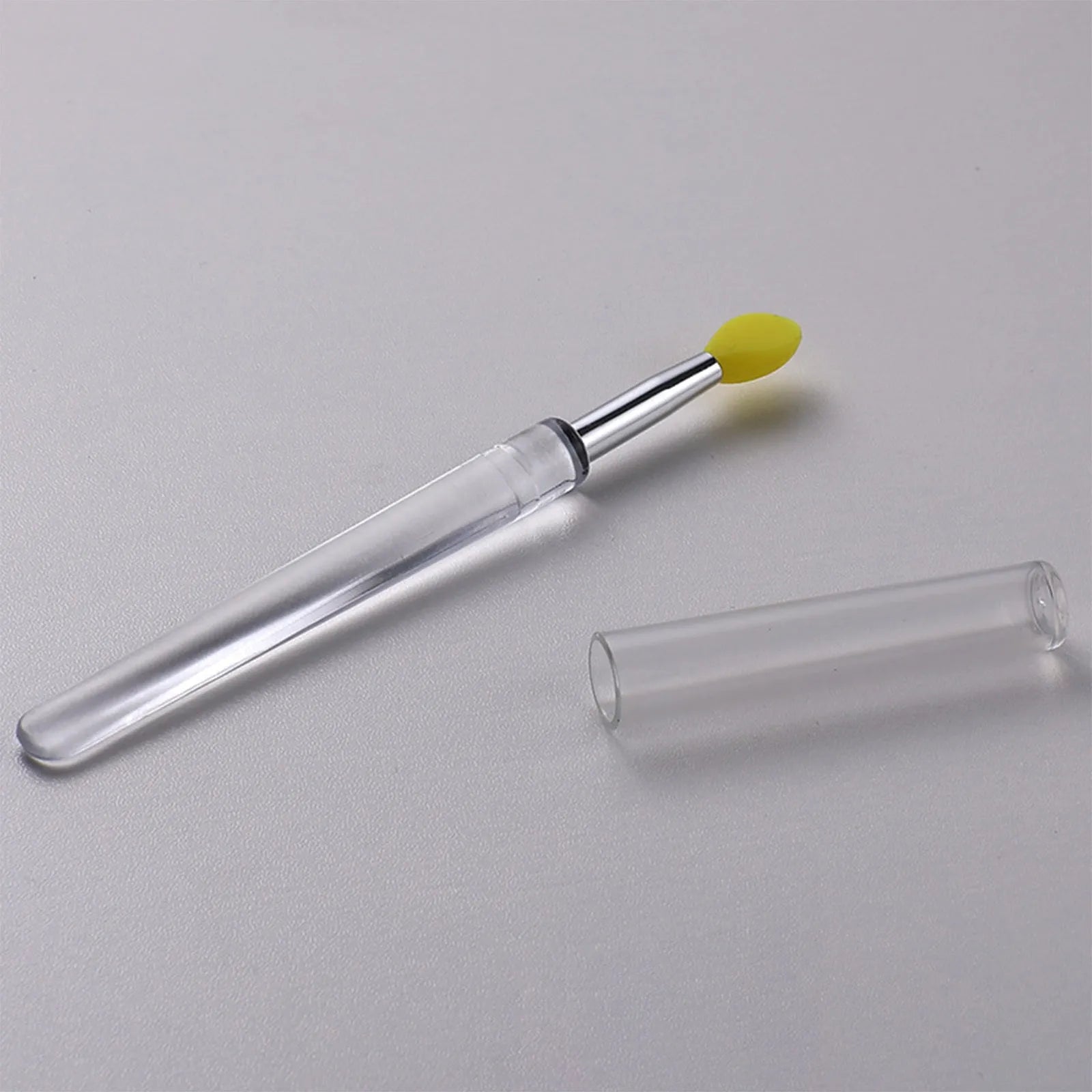 A reusable silicone lip brush with a handle and protective cap, shown in one of eight available colours.