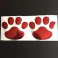 Pair of hand-shaped brush dog footprint PVC car stickers in red, shown against a car bumper.