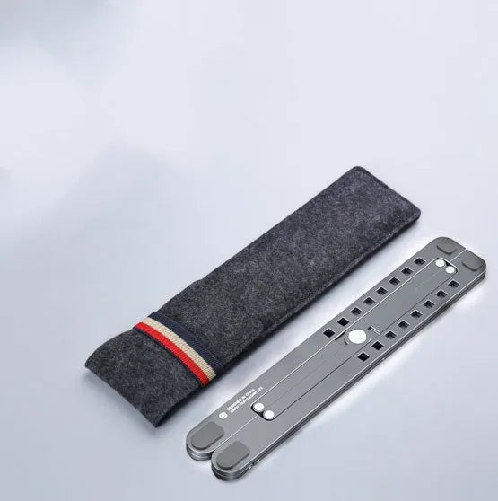 Silver foldable aluminium laptop stand holding a MacBook at an angle, shown next to a backpack.
