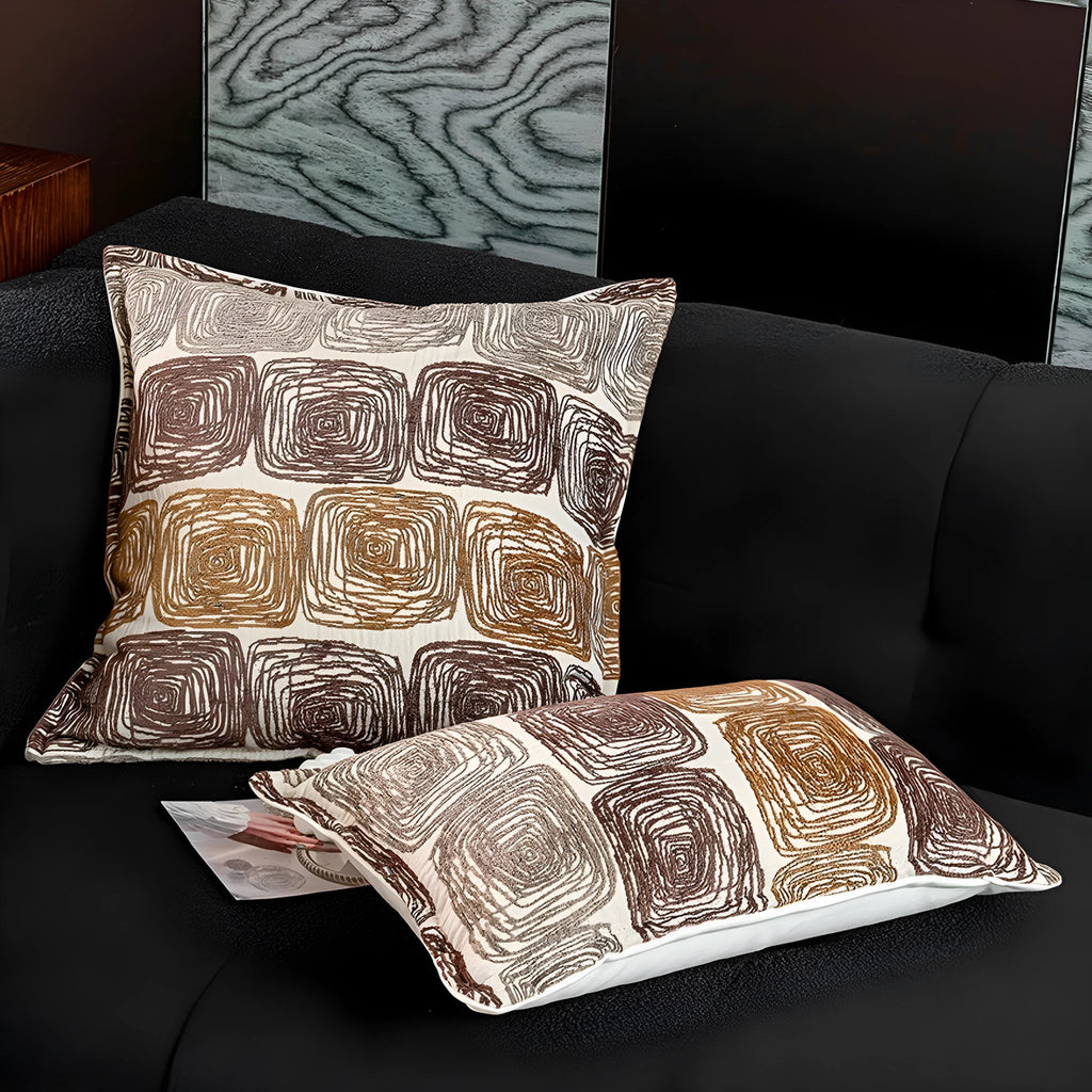 Cream and coffee-coloured abstract coil pattern on a square polyester pillow cover.