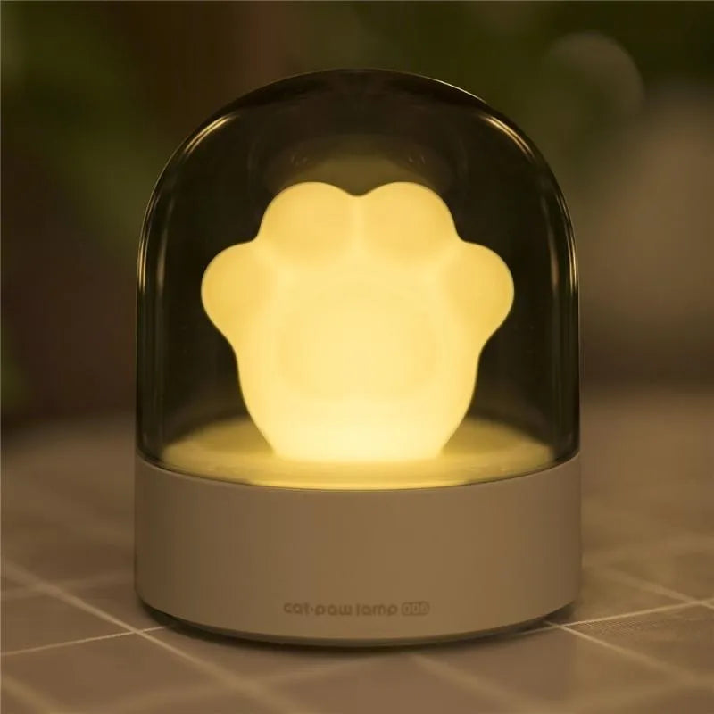Grey cat paw shaped USB rechargeable night light and music box with soft glowing light.