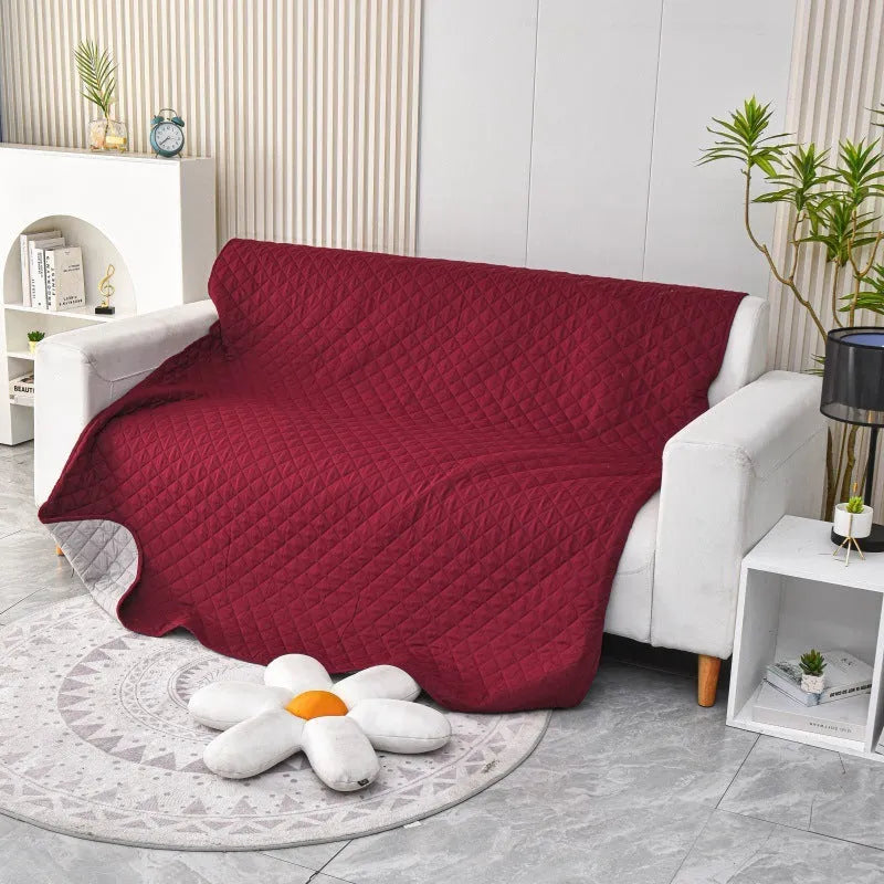 Reversible waterproof dog blanket laid flat on a sofa, showing two colour options.