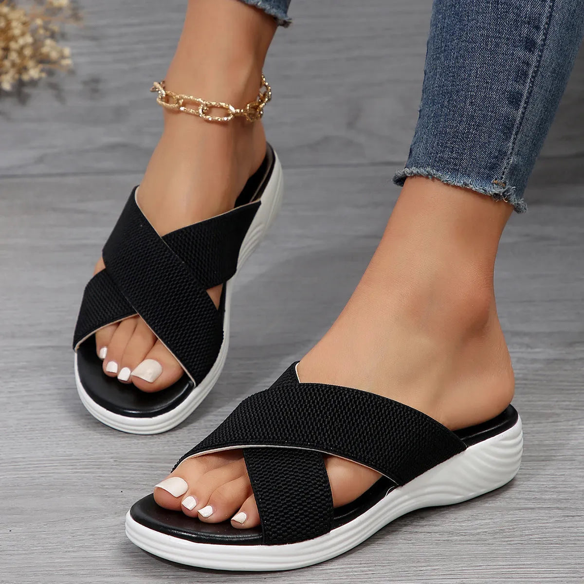 Black wedge platform slippers with a cross strap and open peep-toe design on a white background.