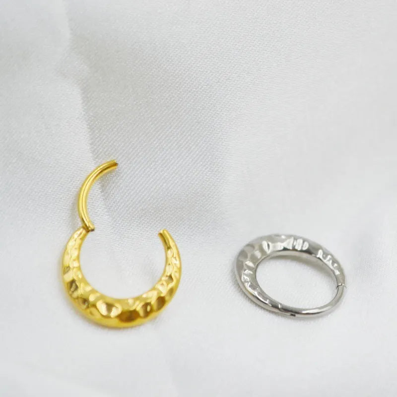 Titanium alloy concave-convex nose ring in gold and silver finishes showing surface texture detail