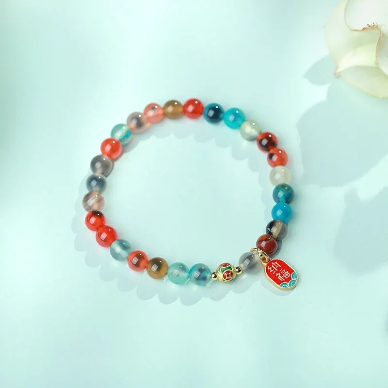 Close-up of a women's snake chain bracelet with colourful agate hearts and detailed copper coins.