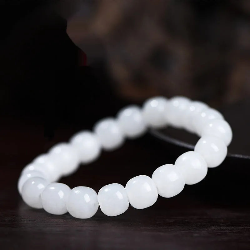 White Hetian jade barrel bead bracelet for men and women on a plain background.