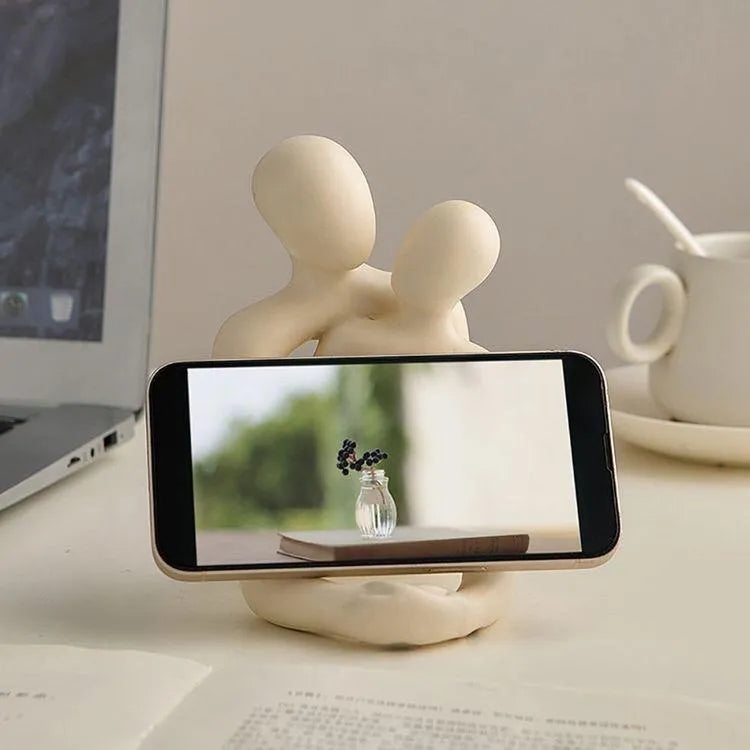 Modern resin statue of an embracing couple in milky white or gold finish on a wooden surface.