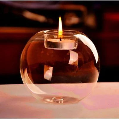 Handmade round hollow glass candle holder with openwork holes, shown on a table.