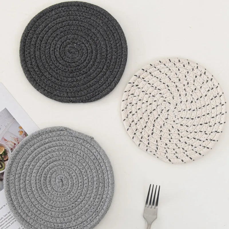 Set of three round grey cotton cord coasters on a wooden table, each 18cm in diameter.
