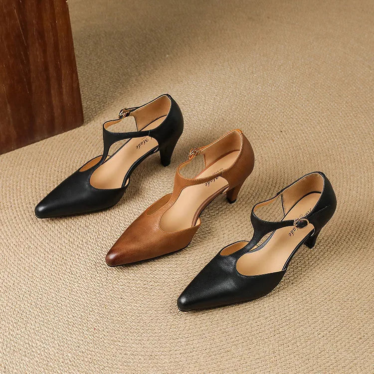 Women's brown retro T-strap closed toe sandals with a stout heel on a wooden surface