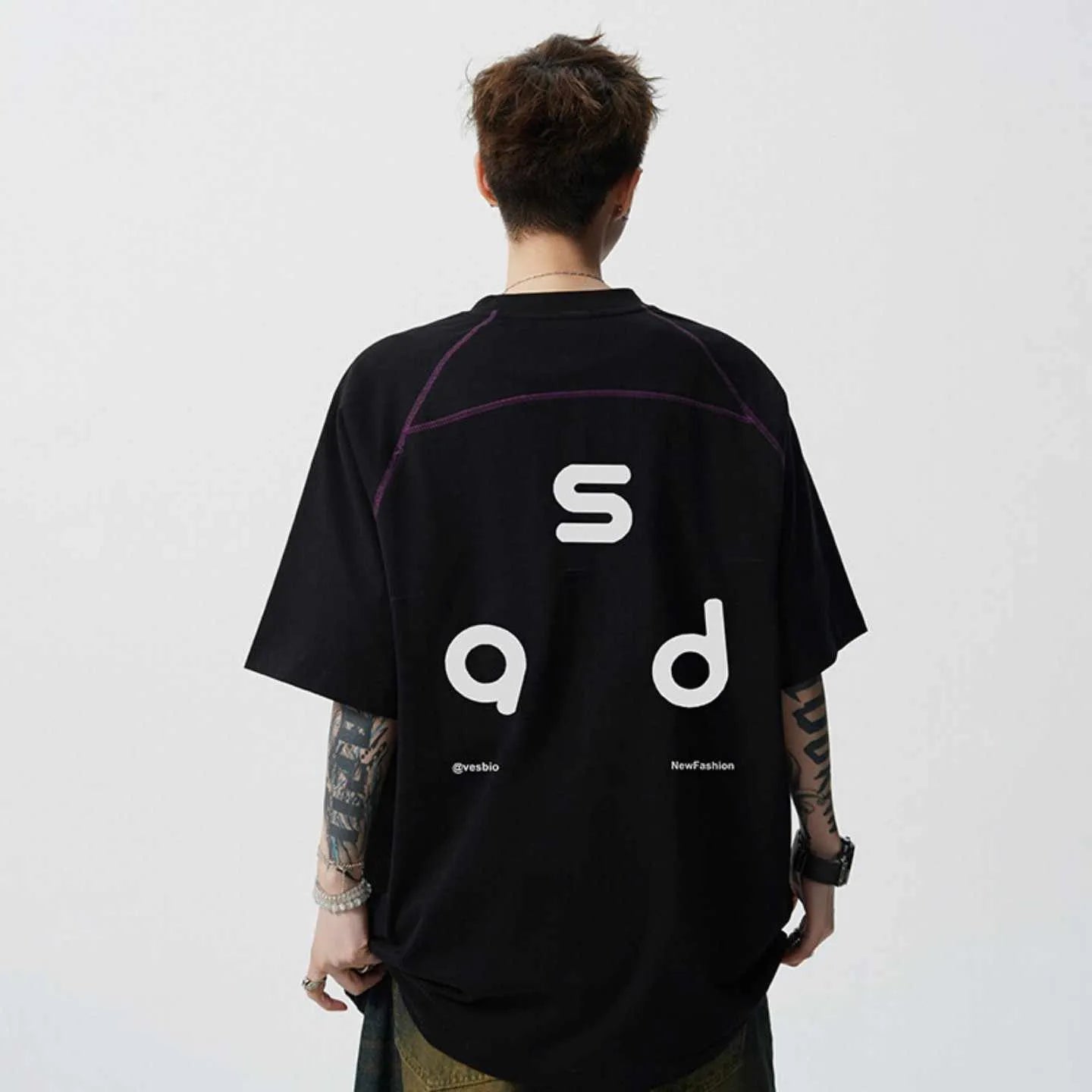 A loose-fitting black cotton short-sleeve T-shirt with a round neck on a hanger.