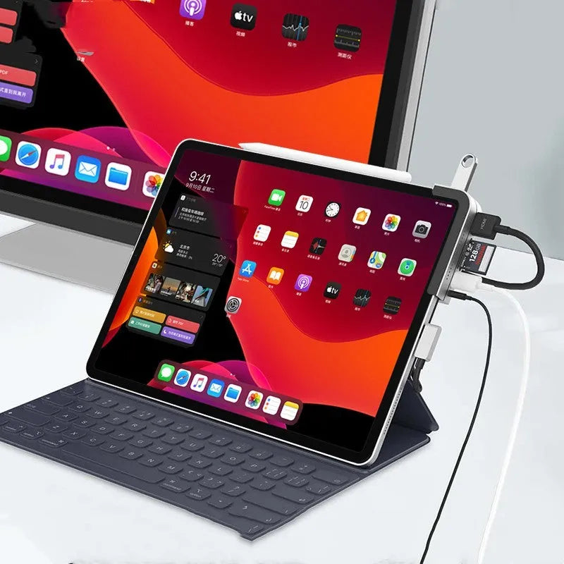 Silver aluminium grey 6-in-1 USB-C docking station for iPad Pro, shown next to a tablet.