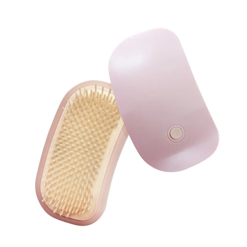 Pink handheld electric pet grooming brush with soft TPE teeth on a white background.