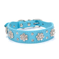 Close-up of a black PU leather dog collar with sparkling rhinestone flowers and a metal D-ring.