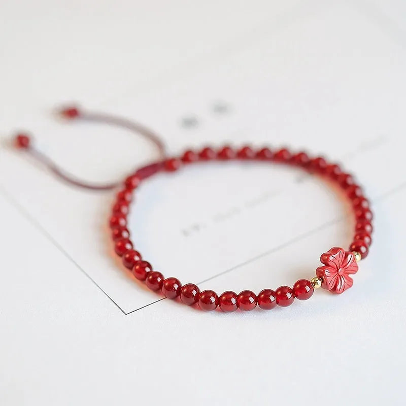 Hand-woven red agate bead bracelet with ethnic design on a wrist.