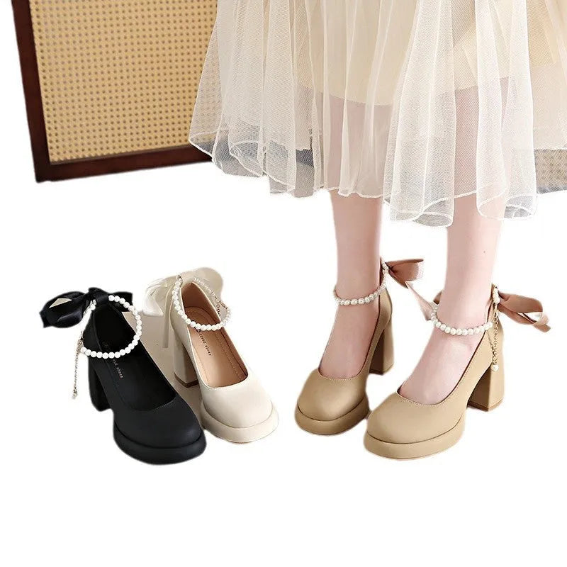 Women's beige Mary Jane shoes with chunky low heel, pearl decoration, and ankle strap buckle on a round toe.