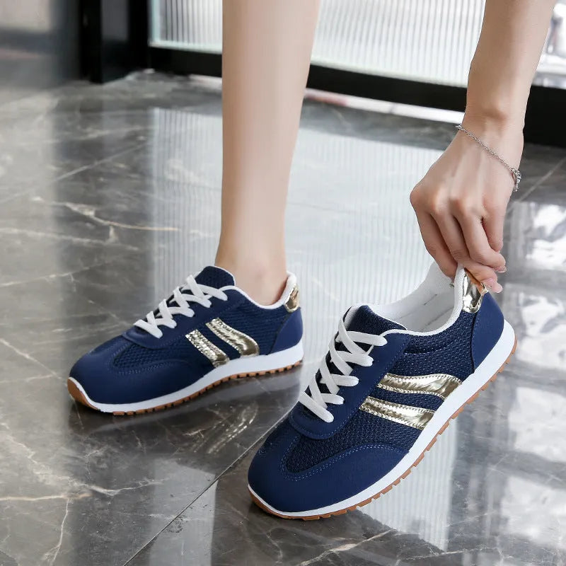 Blue women's casual tennis shoes with cross shoulder straps and white rubber sole on a flat heel.