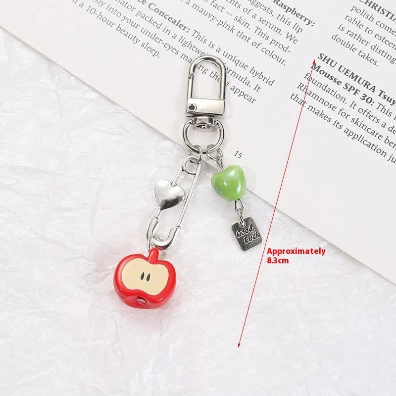 Plastic resin fruit charm keychain with removable rope in strawberry, green apple, and red apple designs.