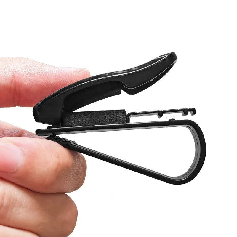 Black plastic car sunshade clip holding sunglasses and parking ticket