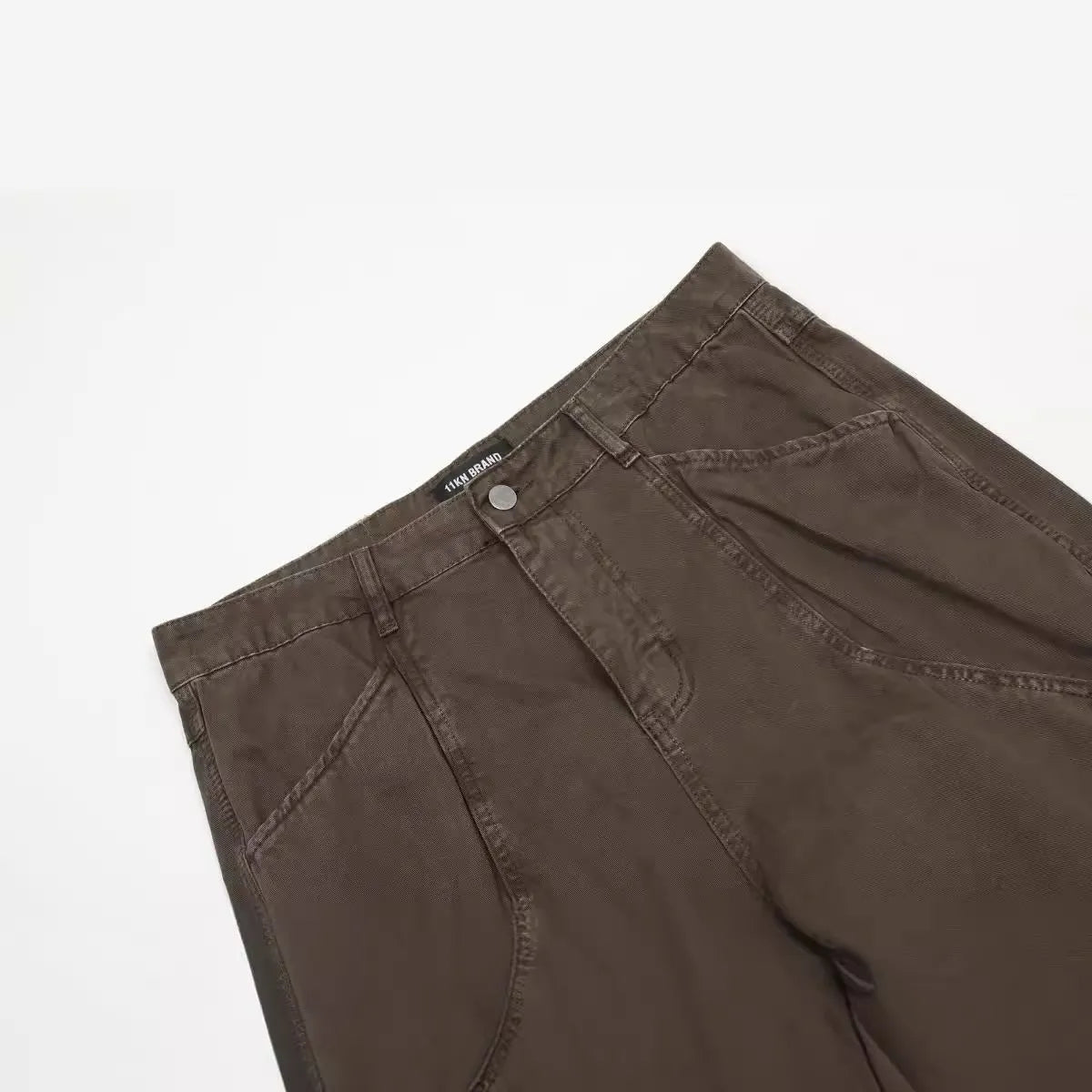 Men's brown loose straight-leg trousers with high waist and wide leg opening on a hanger